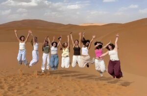 How Much Does a Trip to Morocco Cost? Group of travelers enjoying the Merzouga Desert dunes